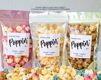 May include: Three clear plastic bags filled with popcorn. Each bag has a white square sticker with black text that reads "Thanks for Poppin' By!" with the names "Tyler + Emily" and the date "04.03.2022".
