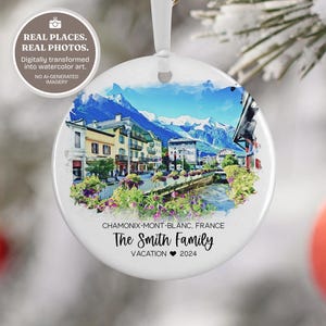 May include: A round white ceramic ornament featuring a watercolor-style illustration of Chamonix-Mont-Blanc, France, with snow-capped mountains and buildings. Text reads: CHAMONIX-MONT-BLANC, FRANCE, The Smith Family, VACATION 2024.