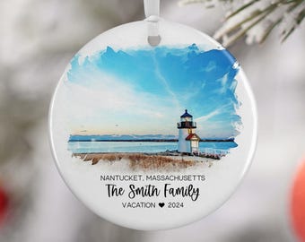 May include: White round Christmas ornament with a watercolor painting of a lighthouse on a beach. The text "NANTUCKET, MASSACHUSETTS The Smith Family VACATION ♥ 2024" is printed on the ornament.