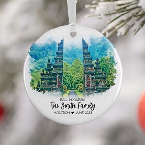 May include: White ceramic ornament with a watercolor painting of a traditional Balinese temple gate. The text "Bali, Indonesia The Smith Family Vacation June 2023" is printed below the image.