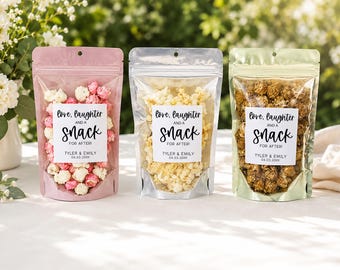 May include: Three stand-up pouches filled with popcorn in pink, silver, and gold metallic finishes. Each bag features a white label with the text: Love, laughter AND A snack FOR AFTER! TYLER & EMILY 04.03.20XX. The bags have clear windows.