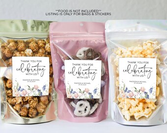 May include: Three clear plastic bags with gold, pink, and white labels. Each bag contains a different type of snack food. The labels have a floral design and the text "Thank you for celebrating with us!" with the names Madison & Michael and the date 07.03.2024.