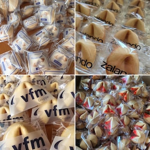 Puede incluir: Una colecci&oacute;n de galletas de la fortuna envueltas individualmente en pl&aacute;stico transparente. Cada envoltorio presenta logotipos y texto impreso, como We eat cookies, zalando, vfm Gruppe, adem&aacute;s de varios dise&ntilde;os gr&aacute;ficos de color rojo.