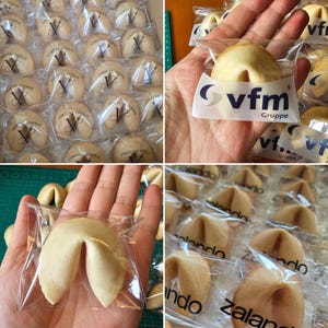 Puede incluir: Una colecci&oacute;n de galletas de la fortuna envueltas individualmente, cada una con un logotipo impreso en el envoltorio de pl&aacute;stico transparente. Algunas galletas muestran el texto vfm Gruppe, otras Zalando o un logotipo en V estilizado.