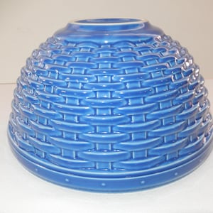 May include: A blue ceramic bowl with a basket weave design. The bowl has a rounded shape with a wide base and a slightly flared rim. The exterior features a detailed woven pattern, and the color is a vibrant, solid blue.