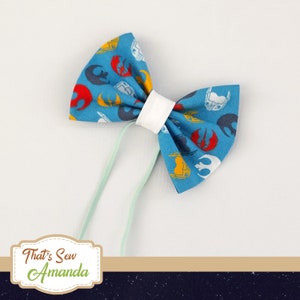 May include: A blue bow tie with a white centre and a pattern of Star Wars symbols in red, yellow and white.