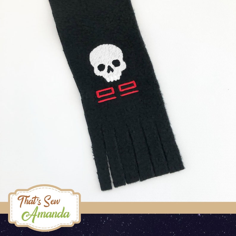 May include: Black scarf with a white skull and red embroidered design. The scarf has a fringed edge. The text "22" is embroidered in red below the skull.