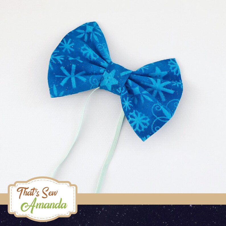 May include: A blue bow tie with a snowflake pattern. The bow tie is tied with a light blue ribbon.