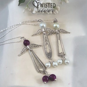May include: Silver angel pendant necklaces. Each necklace features an angel crafted from a spoon, with beaded accents and delicate wing details. The pendants hang from a silver chain. The brand name "Twisted Silver" is visible in the background.