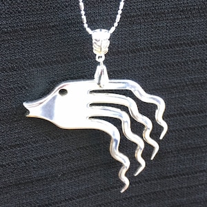 May include: Silver necklace with a pendant shaped like a fish with a long, flowing tail. The pendant is made from a repurposed fork.