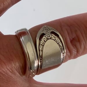 May include: Two silver rings made from spoons, one with a floral design, worn on a finger.