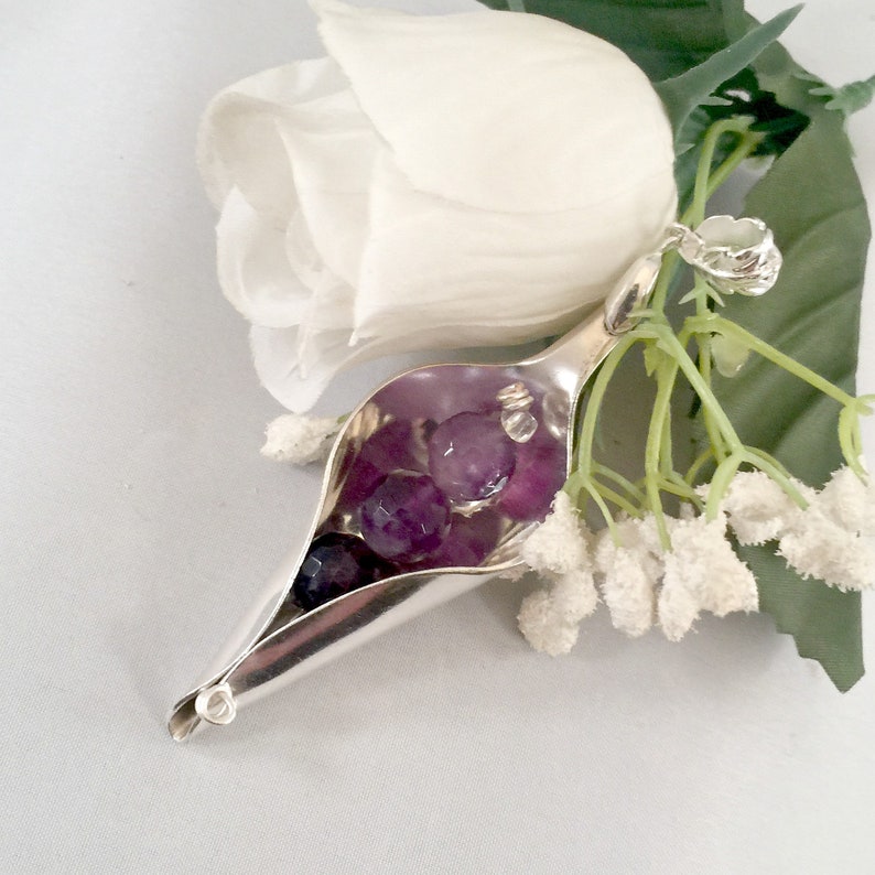 May include: A silver spoon pendant with a curved shape, resembling a flower bud, filled with purple amethyst stones.
