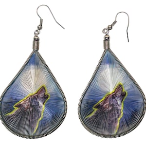 May include: A pair of silver teardrop-shaped earrings with a wolf howling at the moon image. The earrings have a blue and white background with a silver wire frame.