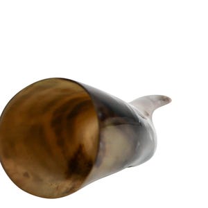 May include: A brown and black drinking horn with a polished interior. The horn is made of natural material and has a unique shape.