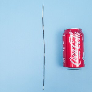 Puede incluir: Una cuerda rayada en blanco y negro junto a una lata roja con el logotipo de Coca-Cola.