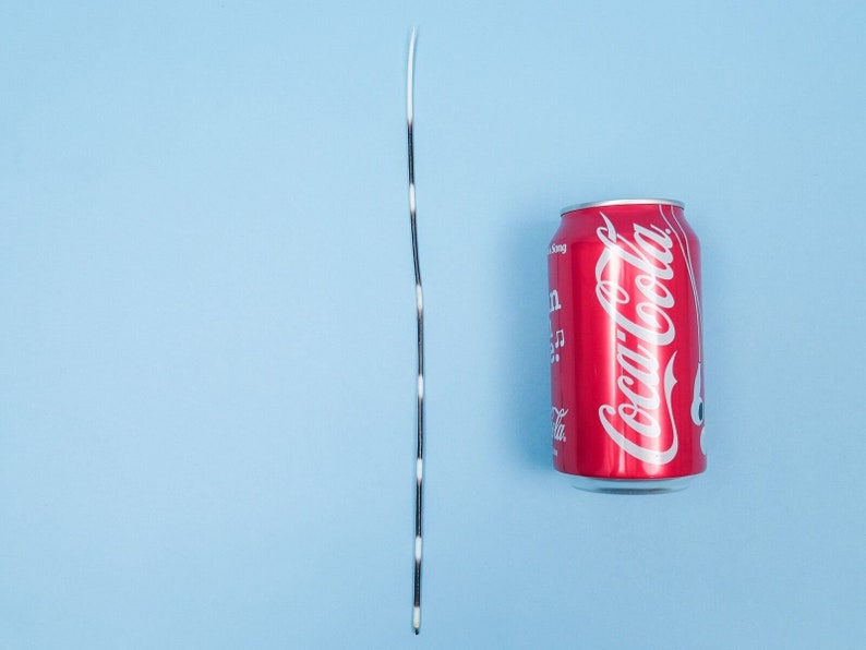 Puede incluir: Una cuerda rayada en blanco y negro junto a una lata roja con el logotipo de Coca-Cola.