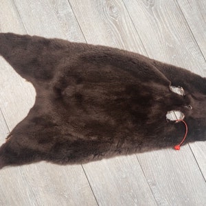 May include: A brown fur pelt with a small hole in the center. The fur is soft and fluffy.