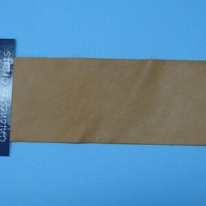 May include: A tan leather sheet with a label that says "Chichester Crafts" and has a handprint logo.