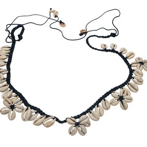 May include: A black cord necklace with white shell flower accents.