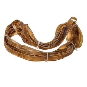 May include: A bundle of brown leather strips tied together with white plastic ties. The leather is thin and flexible, and it appears to be used for crafting.
