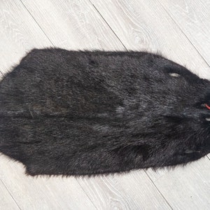 May include: A black fur pelt with a red string tied around it.