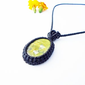 May include: A green and white stone pendant with a black cord necklace. The stone is set in a black macrame knot.