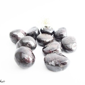 May include: A group of ten smooth, dark red and black tumbled stones. The stones are arranged in a cluster on a white background.