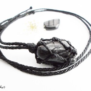 May include: Black gemstone pendant necklace with a black cord. The gemstone is wrapped in a black macrame knot.