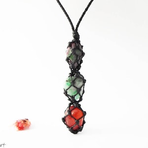 Könnte beinhalten: Eine schwarze Schnurkette mit drei Edelsteinperlen in einem Makramee-Knoten. Die Perlen sind grün, rosa und rot.