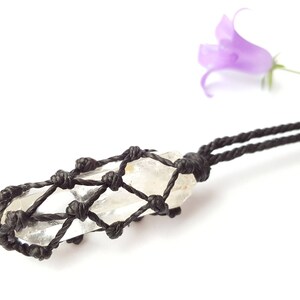 May include: A clear quartz crystal pendant wrapped in a black macrame cord necklace.