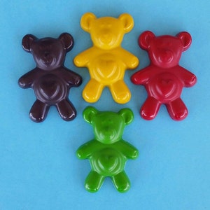 May include: Four small teddy bear shaped crayons in different colors: brown, yellow, red, and green.