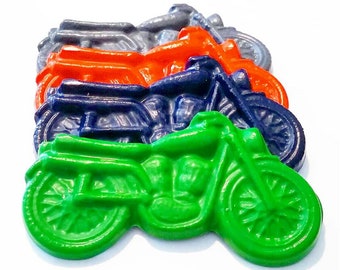 May include: Four colorful crayon motorcycle shaped toys. The crayons are stacked on top of each other. The top crayon is green, the next is blue, the next is orange, and the bottom crayon is gray.
