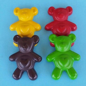 May include: Four small bear-shaped crayons in yellow, red, brown, and green. Each crayon has a heart-shaped design in the center.