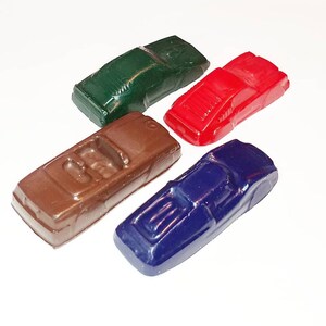May include: Four miniature toy cars in different colors: green, red, brown, and blue. The cars are made of plastic and have a smooth, glossy finish.