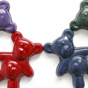 May include: Four colorful teddy bear shaped crayons in purple, red, blue, and green.