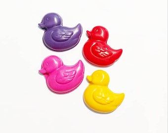 May include: Four colorful rubber duck crayons in purple, red, pink, and yellow.