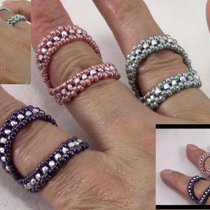 Könnte beinhalten: Vier Perlenringe in verschiedenen Farben, darunter Silber, Rosa und Lila. Die Ringe bestehen aus kleinen Perlen und haben eine Lücke in der Mitte.