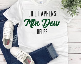 Puede incluir: Camiseta blanca con texto negro que dice "Life Happens Mtn Dew Helps" en verde.