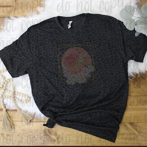 May include: A black t-shirt with a leopard print design. The shirt has a floral graphic with the text "Southern Knot Designs" in a gold frame.