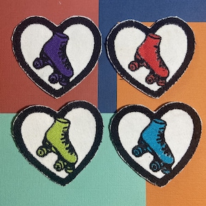 May include: Four embroidered iron-on patches in the shape of hearts with roller skate designs. Each heart features a different coloured roller skate: purple, red, green, and blue.