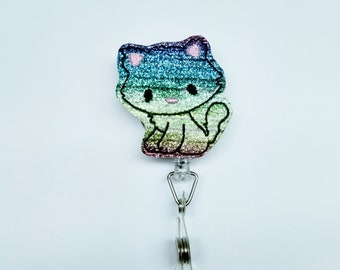 May include: A rainbow glitter cat charm with a silver retractable badge holder. The cat charm is a cartoon style with pink ears and a black outline.