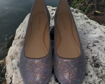 Op de afbeelding: Een paar grijze glitter ballerina's met een afgeronde neus. De schoenen hebben een eenvoudig ontwerp en zijn gemaakt van een zacht, comfortabel materiaal. De merknaam "Dream Pairs" staat gedrukt aan de binnenkant van elke schoen.