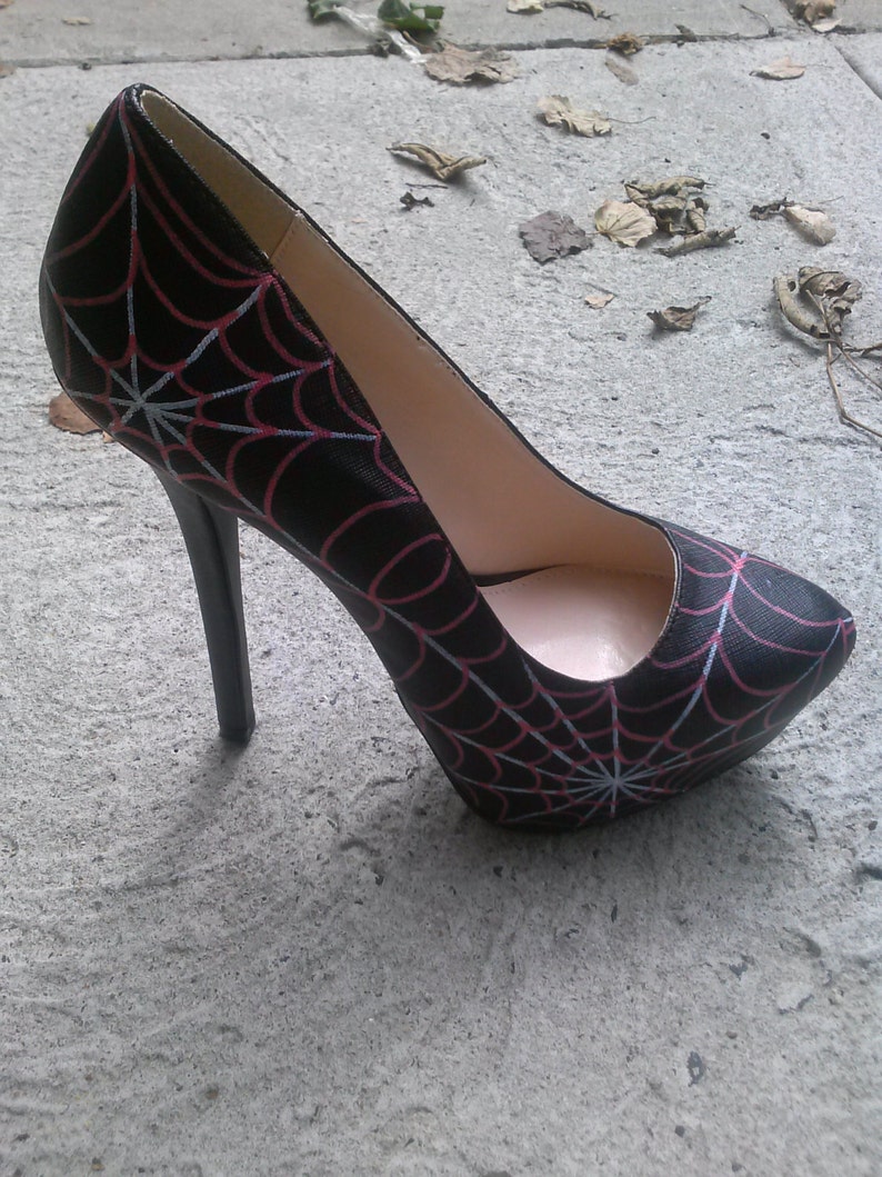 May include: Black high-heeled pump with a spiderweb design in red and white.