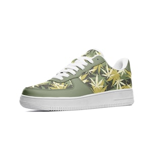 Puede incluir: Zapatillas verdes y amarillas con un patrón de hojas de marihuana. Las zapatillas tienen cordones blancos y una suela blanca.