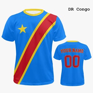 May include: Blue t-shirt with a yellow collar and a red and yellow diagonal stripe. A yellow star is on the left chest. The back of the shirt has the text "YOUR NAME" above the number "00" in red. The text "DR Congo" is in the upper right.