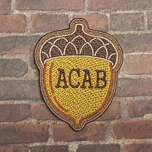 May include: A brown and yellow embroidered patch shaped like an acorn with the text "ACAB" inside.