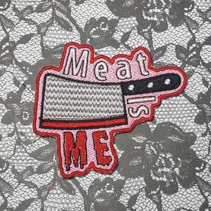 May include: Pink and red embroidered patch with a butcher knife and the text "Meat Slices Me".