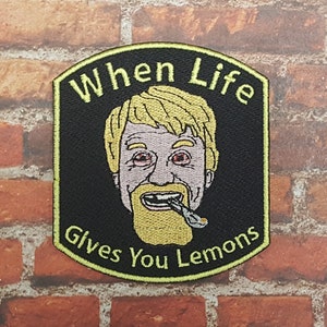 Könnte beinhalten: Ein schwarzer und gelber gestickter Aufnäher mit einem Cartoon-Bild eines Mannes mit Bart, der eine Zigarette raucht. Der Text auf dem Aufnäher lautet "When Life Gives You Lemons".