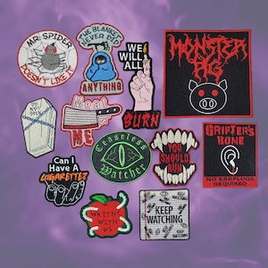 Puede incluir: Una colección de parches bordados con varios diseños y texto. Los parches incluyen una araña, un ataúd, un cerdo, una mano sosteniendo un fósforo y frases como "Meat Me" y "Keep Watching". Los parches son de varios colores.