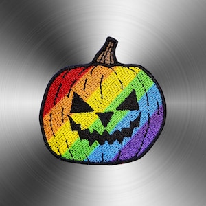 Puede incluir: Un parche bordado con forma de calabaza de Halloween. La calabaza presenta un vibrante patrón de rayas con los colores del arcoíris en su superficie, con un tallo bordado en negro y una cara negra dentada que consiste en dos ojos triangulares y una amplia sonrisa.